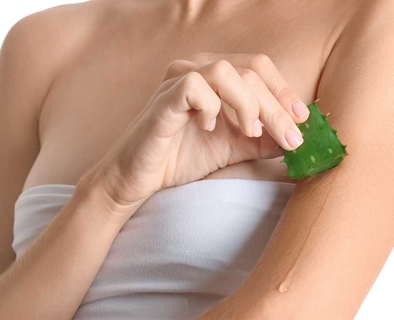 Frau reibt Aloe Vera an Haut